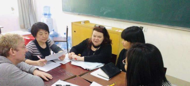Maree with a group of teachers sitting around a table in a classroom having a discussion about teaching English.